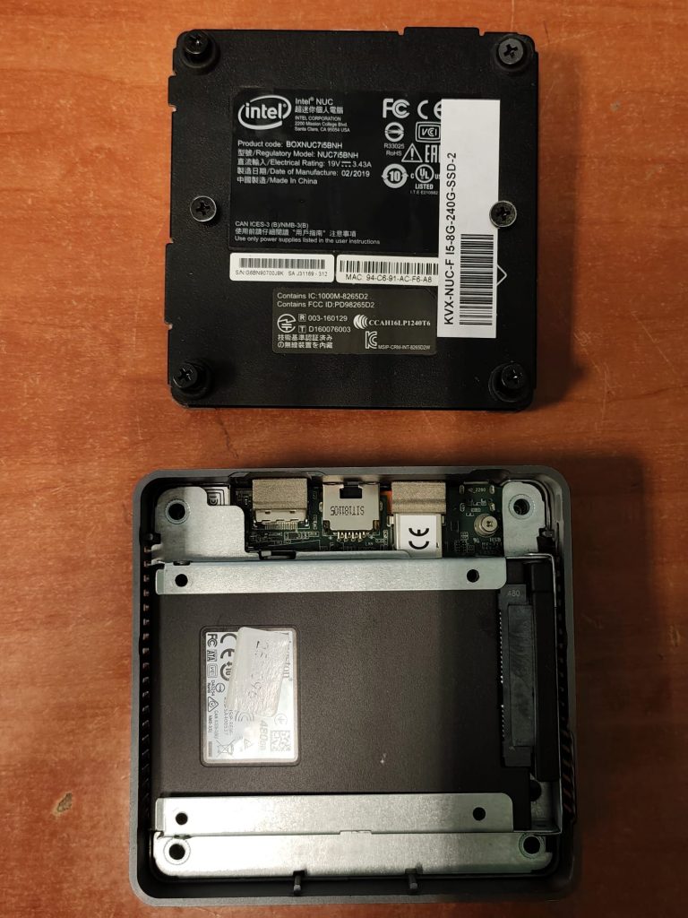 Vista general del Mini PC Intel NUC BOXNUC7i5BNH abierto junto a su tapa inferior de especificaciones.