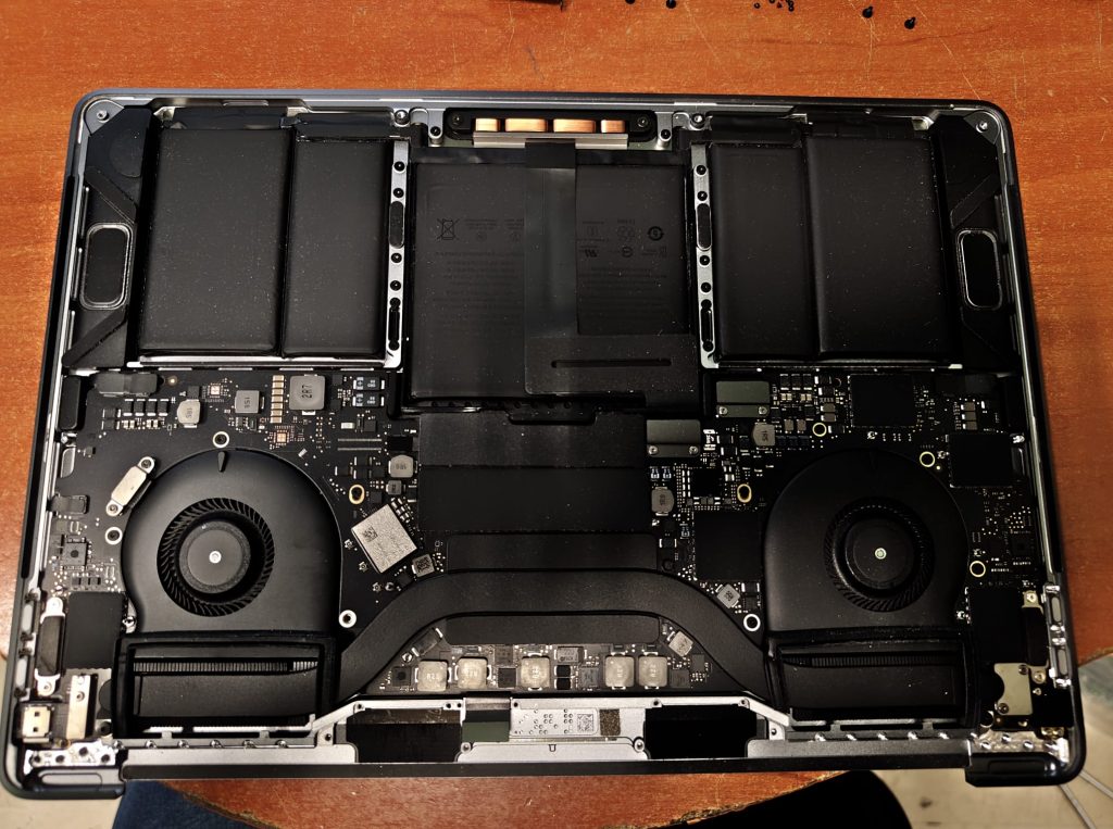 Vista interna de un MacBook Pro 2018 mostrando la placa lógica, ventiladores y batería durante el proceso de desmontaje.