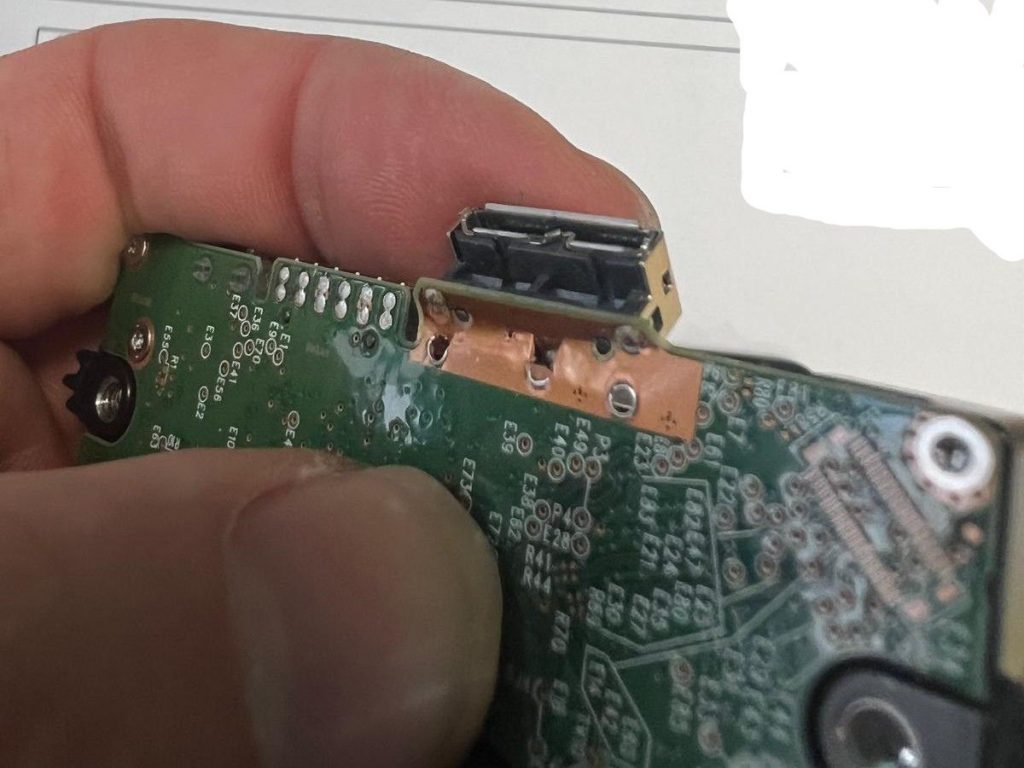 Close-up de la PCB mostrando las pistas de datos arrancadas que requieren micro-soldadura.