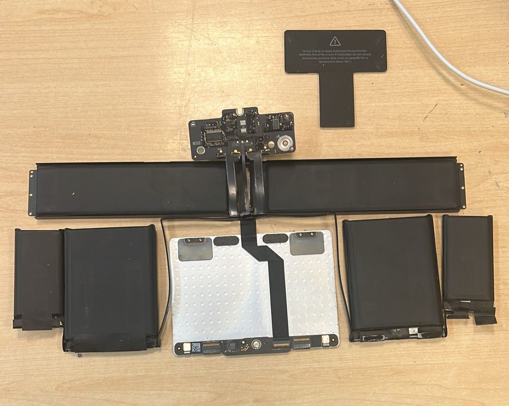 Despiece total de la batería y trackpad usados tras ser retirados del equipo.