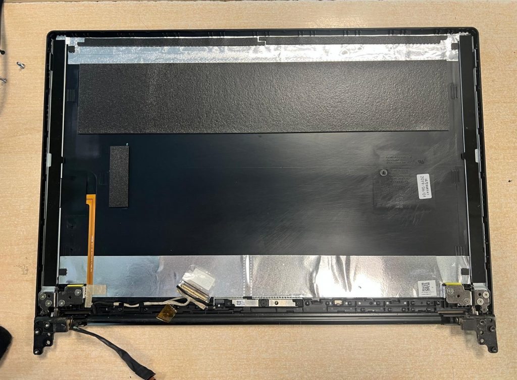 Interior de la tapa superior de la laptop con el panel LCD retirado y bisagras expuestas.