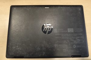 Vista posterior de la laptop HP Pro x360 con etiquetas de dotación educativa.