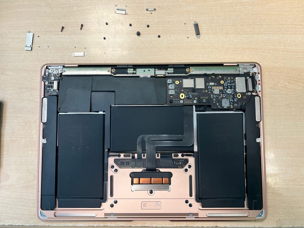 Chasis de MacBook Air sin placa base y tornillería organizada para reparación.