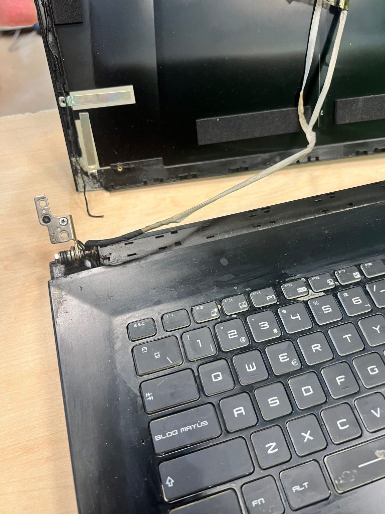 Detalle del soporte de la bisagra izquierda roto y cables de antena Wi-Fi expuestos en MSI MS-1799.