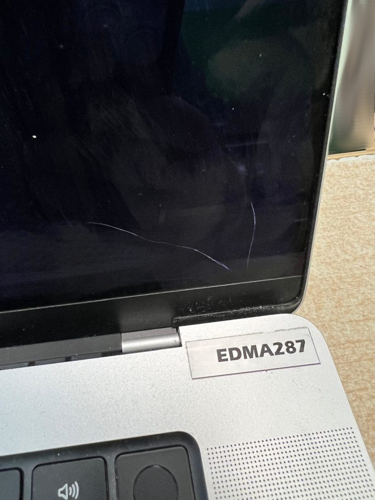 Detalle de fisuras y daños físicos en el cristal de la pantalla de una MacBook Pro.