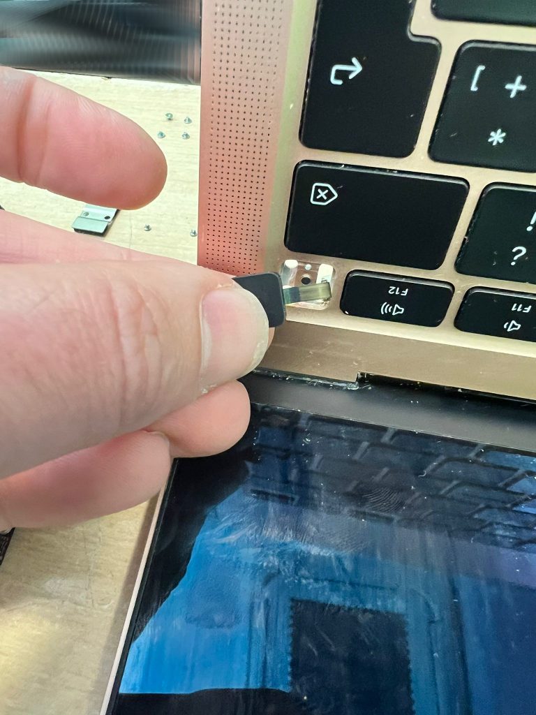 Técnico instalando el botón de encendido con Touch ID en MacBook Air.