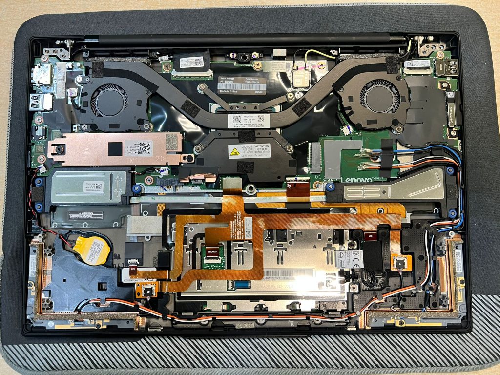 Chasis interno del portátil Lenovo sin la batería, dejando ver el cableado y conectores de la pantalla.