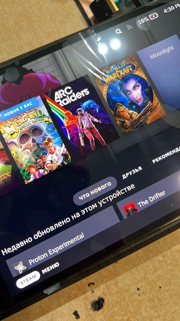 Steam Deck OLED completamente reparada y encendida en la mesa de trabajo del taller, mostrando la biblioteca de juegos tras el cambio de pantalla.