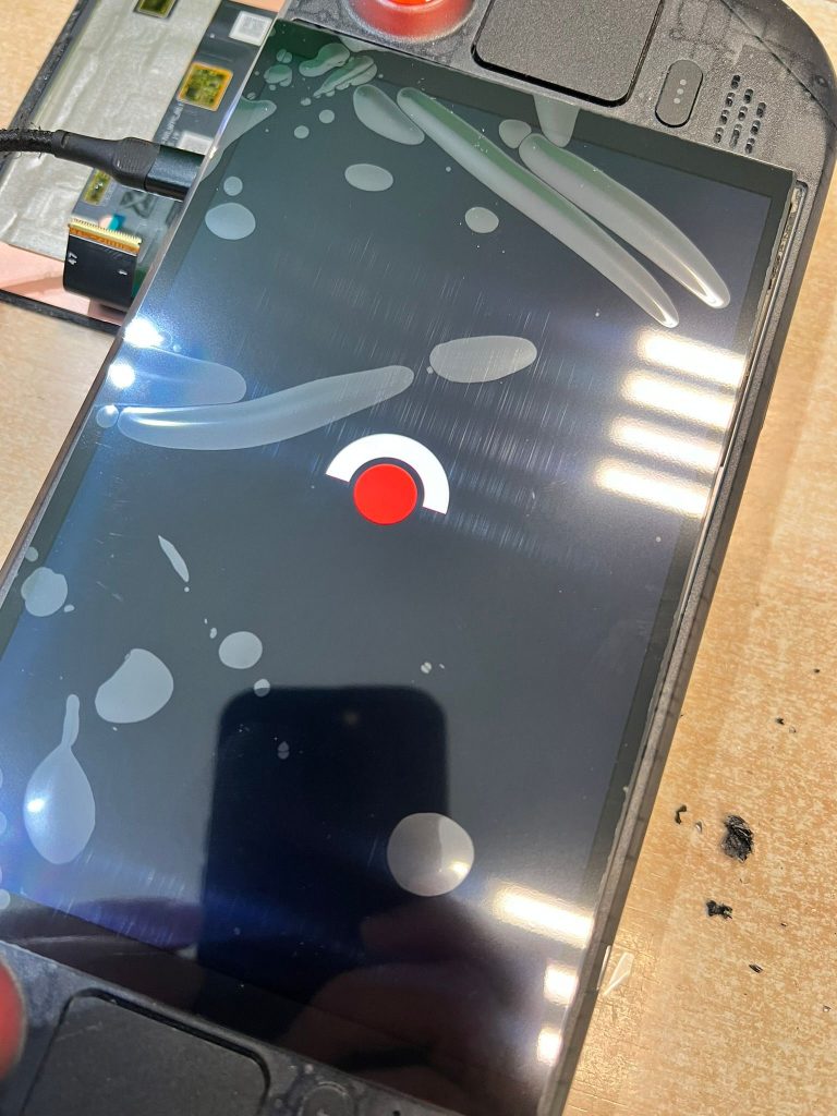 Prueba de funcionamiento de la nueva pantalla OLED instalada en la Steam Deck mostrando el logo de carga rojo sobre fondo negro.