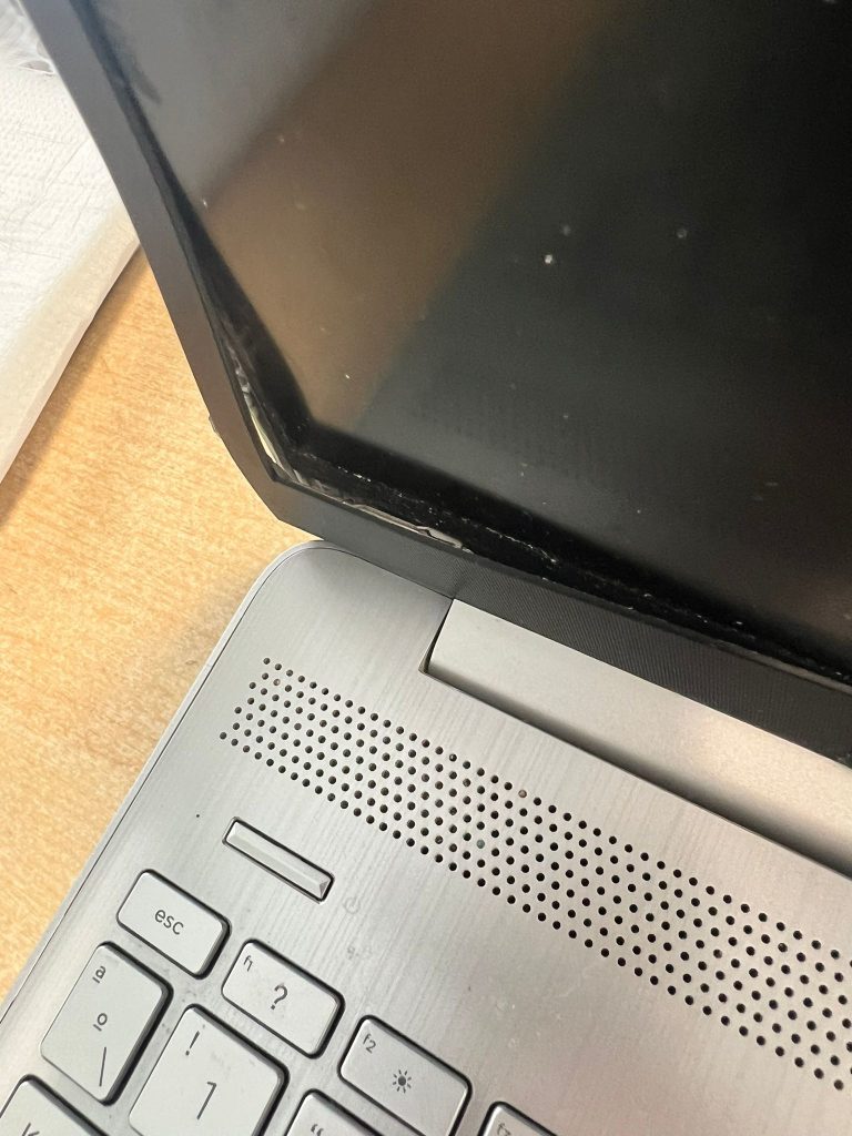 Detalle del marco de pantalla HP desprendido por rotura de los soportes de la bisagra.