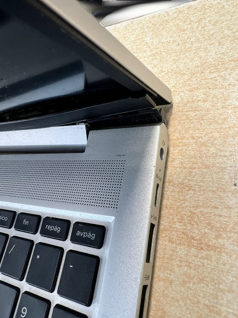 Detalle de la tapa superior desprendida y daños estructurales en la zona de la bisagra.