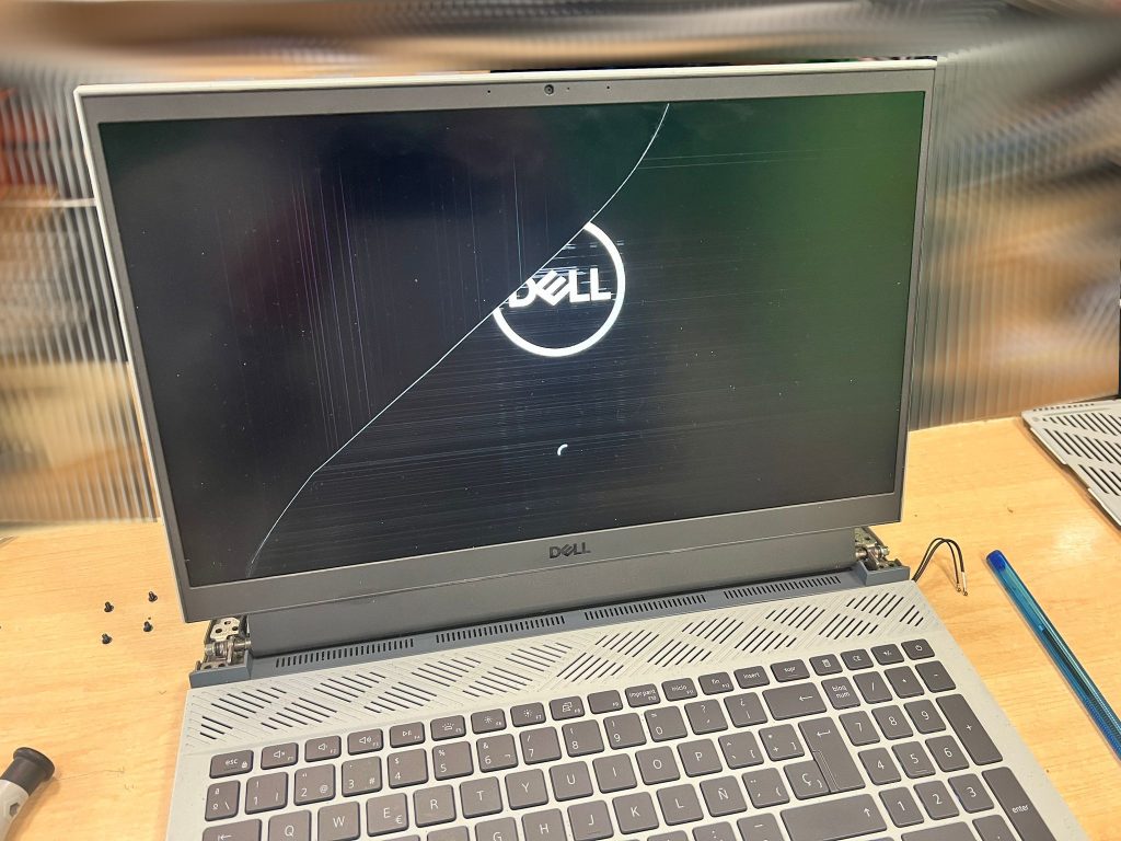 Laptop Dell G15 con pantalla LCD rota mostrando líneas horizontales y grietas.