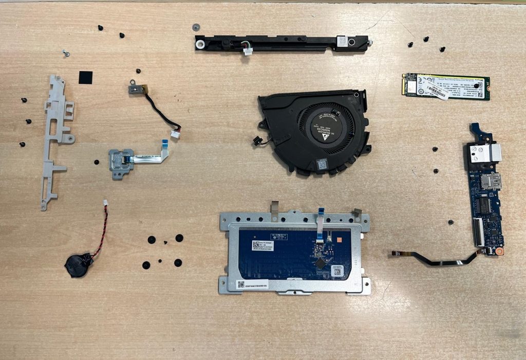 Organización de piezas internas (ventilador, touchpad, placa I/O) durante la reparación.