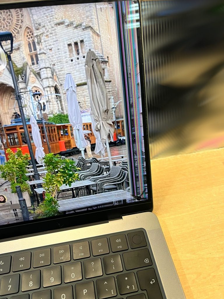 MacBook Pro A2918 con pantalla dañada mostrando líneas verticales de colores.