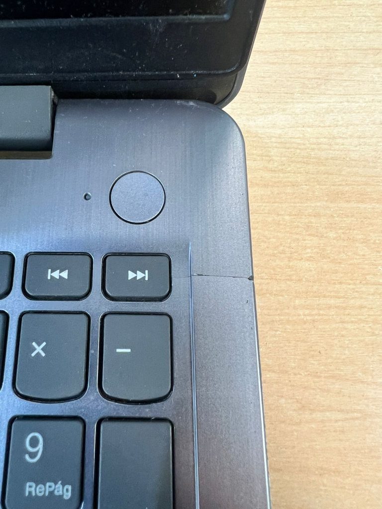 Primer plano de grieta en la esquina superior del palmrest cerca del botón de encendido.