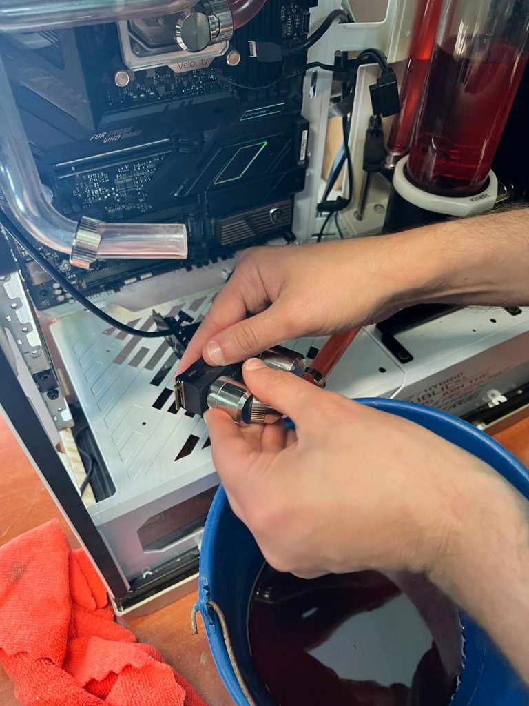 Técnico drenando manualmente el líquido refrigerante rojo hacia un cubo de servicio.