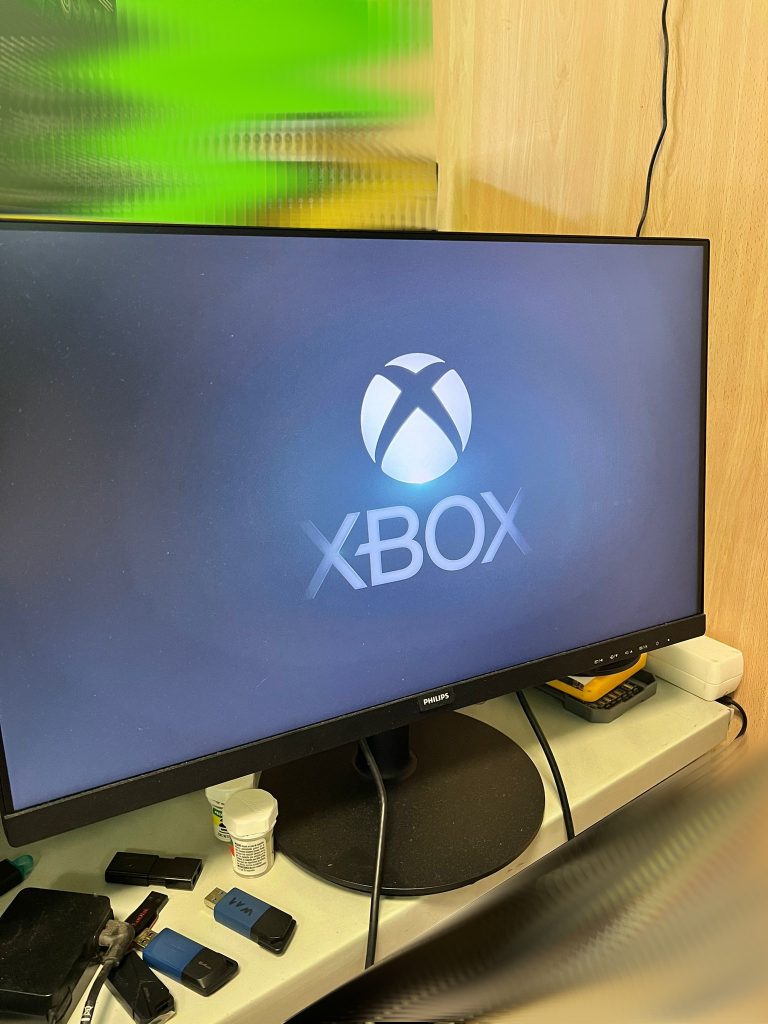 Consola Xbox Series X reparada mostrando el logo de inicio en un monitor.