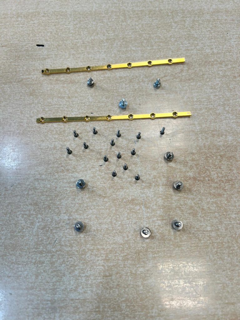 Organización de tornillos y piezas de soporte metálico durante la intervención técnica.