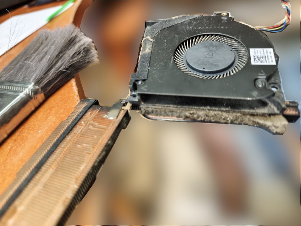 Limpieza manual con brocha de las rejillas del ventilador de un Alienware m15 obstruidas por polvo.