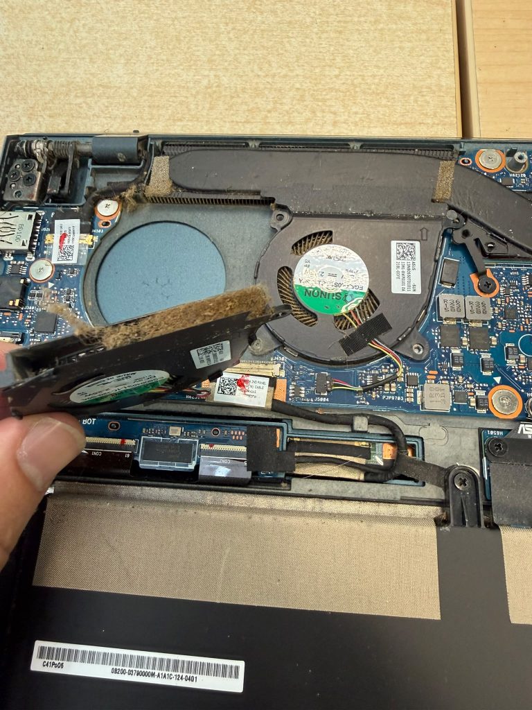 Extracción de acumulación de polvo y pelusa en el ventilador de un portátil Asus.