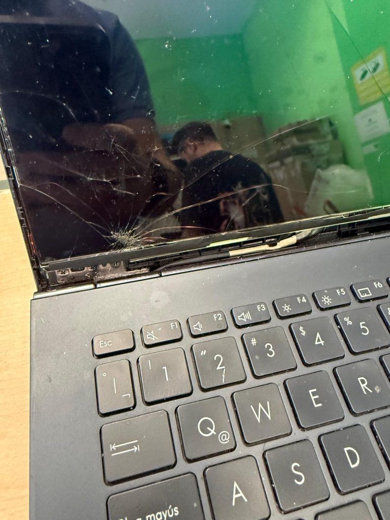 Primer plano de la fractura del cristal OLED y bisagra izquierda en portátil Asus Zenbook.