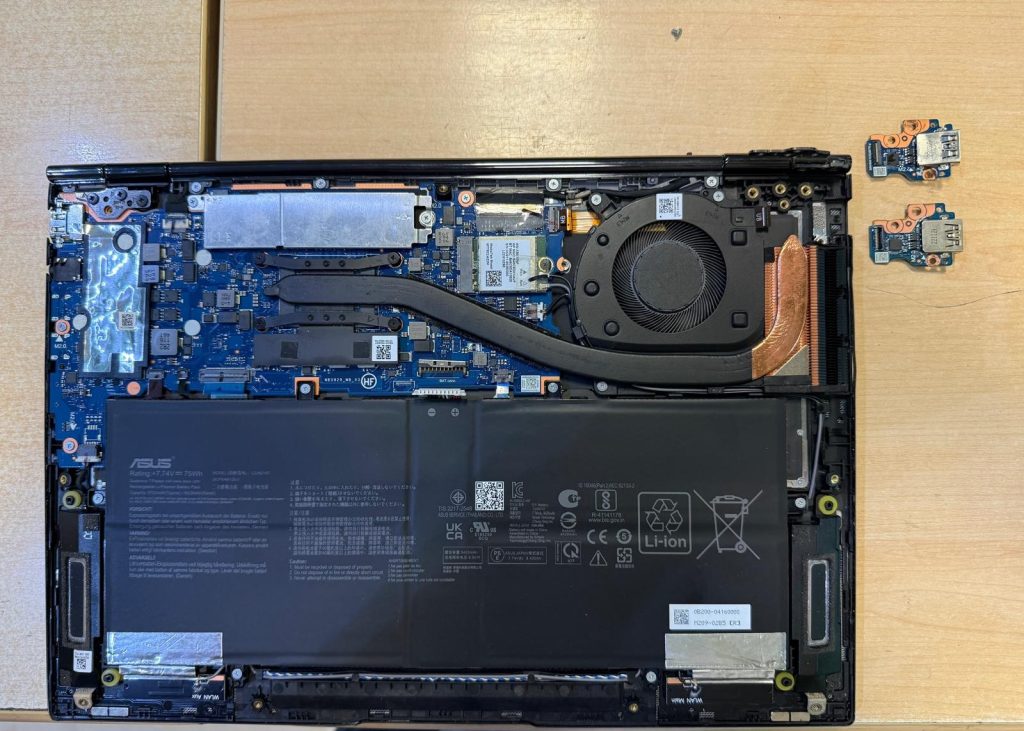 Vista interior del Asus Zenbook UM3402Y con disipador, batería C21N2107 de 75Wh y placas USB al lado.
