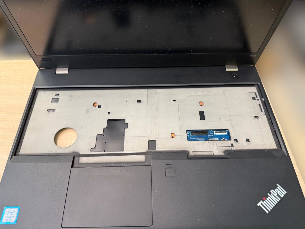 Parte superior del teclado retirada mostrando el blindaje metálico y conector flex en la ThinkPad P52s.