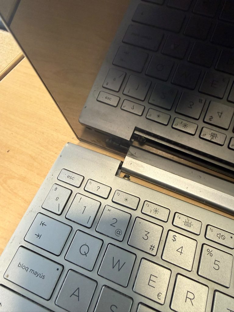 Detalle del anclaje de bisagra roto levantando la carcasa superior junto a la tecla escape en HP Envy 13.
